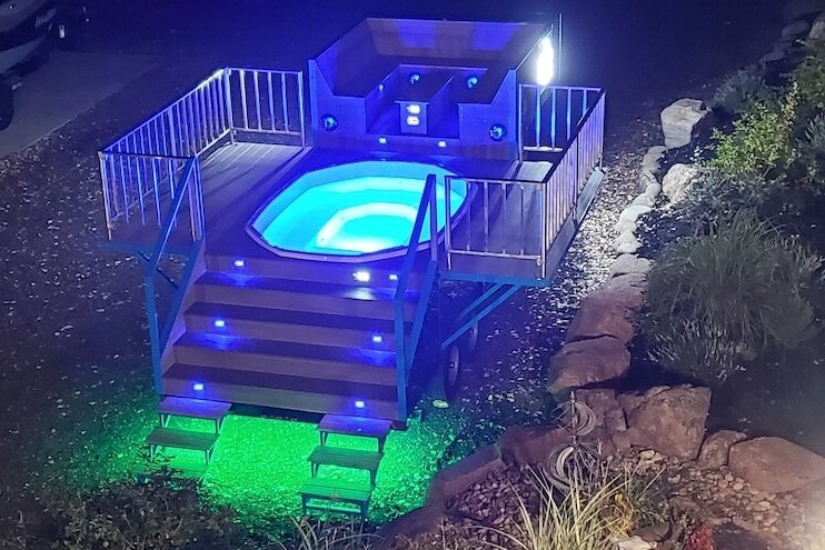 Actual Party Tub Social trailer illuminated at night with glowing hot tub and colorful lights